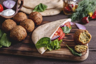 Falafel, taze sebze, sos ve Pide tahta masada ekmek