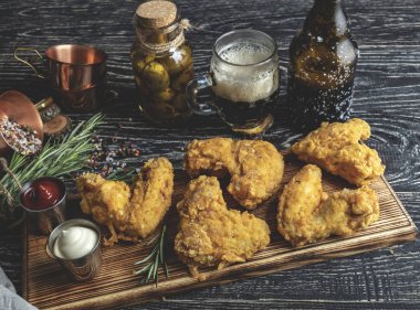 karanlık bir yüzey üzerinde meyilli, kırmızı ve beyaz soslu kızarmış tavuk kanadı