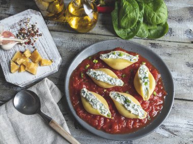Ispanak ve peynir, domates sos plaka üzerinde pişmiş makarna conchiglioni dolması