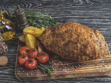 Kavrulmuş domuz eti nağmeleme, patates ve domates ile bir kesme tahtası üzerinde rulo