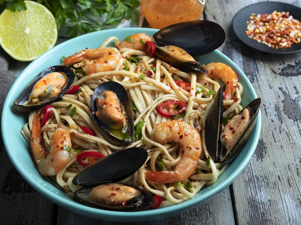 cooking noodles pasta with shrimp and mussels , spice , on the plate. Closeup.