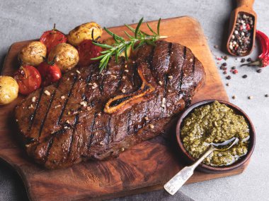Kemikli ızgara biftek, ahşap ahşap soslu yeni patates domatesi.