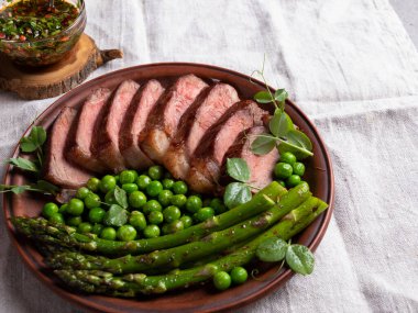 Kızarmış biftek, yeşil bezelye, kavrulmuş kuşkonmaz, yakın plan.