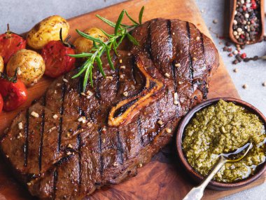 Kemikli, patatesli, domatesli, ahşap tahtalı, soslu biftek.