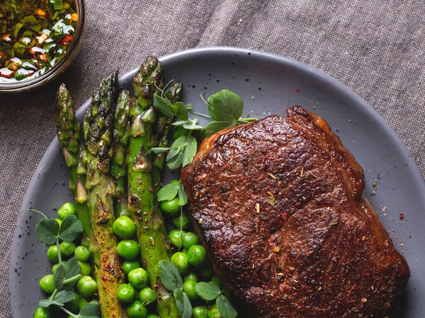 juicy roasted meat steak, mutton with asparagus green peas on a plate, close up