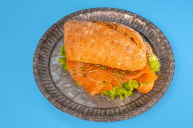 Somonlu sandviç ve mavi arka planda salata.