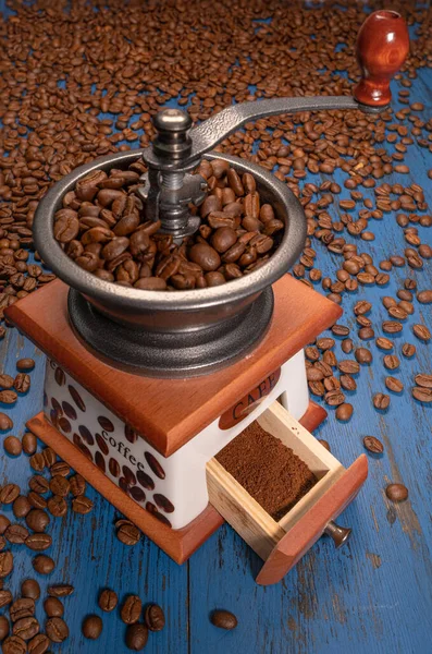 Molinillo de café manual con granos de café sobre un fondo de madera azul — Foto de Stock