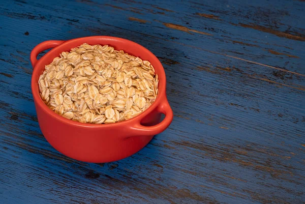 Oatmeal with nuts in a mug on a blue wooden background — Stock Photo, Image