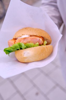 Kadın hamburgeri somon ve salatayla tutuyor.