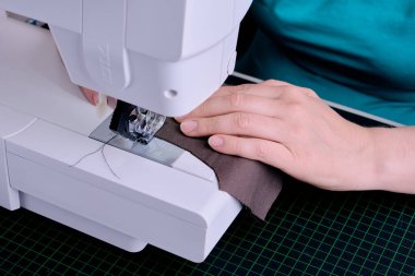 Genç bir terzinin eli, terzilerin geleneğine uygun olarak elbise dikmek için koruyucu bir maske takar..