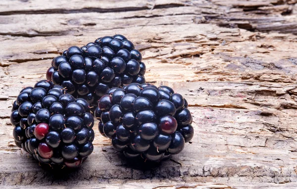 旧木制背景上的三个大黑莓巨无霸 — 图库照片