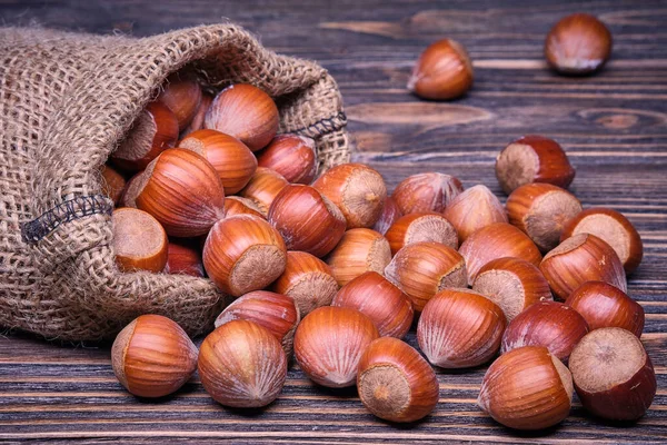 Lískové oříšky v tašce, vegetariánské jídlo v dřevěných miskách, na starém dřevěném pozadí — Stock fotografie