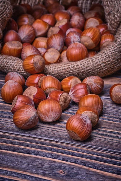 Lískové oříšky v tašce, vegetariánské jídlo v dřevěných miskách, na starém dřevěném pozadí — Stock fotografie