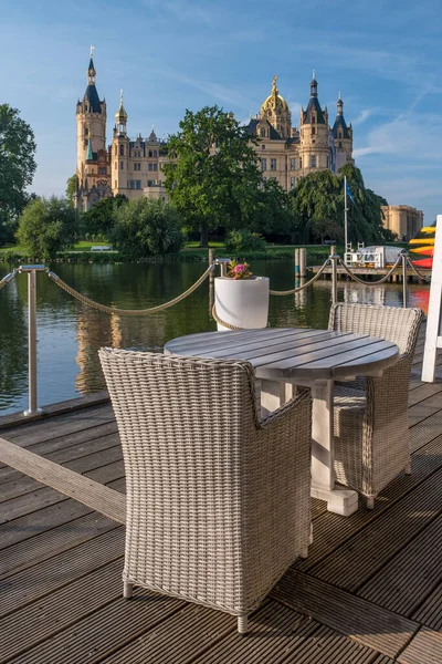 Cadeiras vazias em café com um belo castelo em Schwerin, no fundo. — Fotografia de Stock