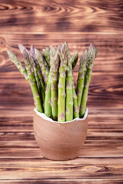 Asperges dans un bol en terre sur fond de bois rustique — Photo