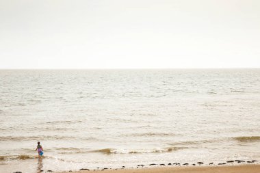 Bir kovayla denize giden genç bir kızın arkasından.