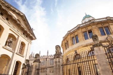 There are thirteen square pillars topped by head-and-shoulder busts marking the front boundary of the sheldonian theatre in oxford clipart