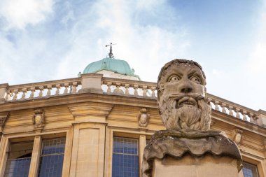 Oxford 'daki Sheldonian Tiyatrosu' nun ön sınırını belirleyen kafa ve omuz büstleri ile kaplı 13 adet kare sütun var.