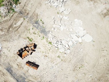 Yerdeki ağır boş kazıcı kovası kuş bakışı bir yerden alınmış.