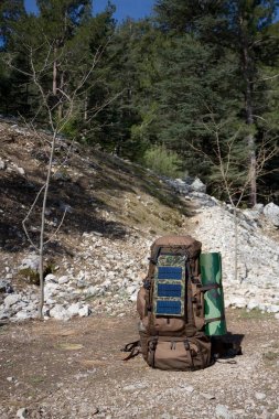 Büyük bir turist sırt çantası bir orman Glade duruyor. Üzerinde taşınabilir bir güneş pili monte edilir. Güneşli bir gün. Bahar. Likya yolu 'nda yürüyüş yapın. Türkiye.