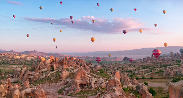 Красочные воздушные шары, летящие над горным ландшафтом в Каппадокии, Национальный парк Гореме, Турция.