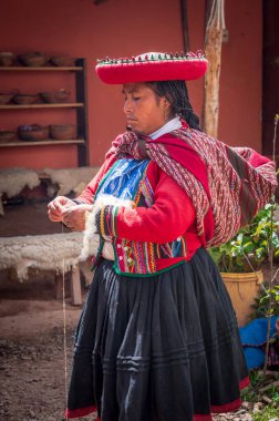 Chinchero, Peru - March 9, 2015: Peruvian woman dressed in traditional clothes while working on homemade wool industry using traditional techniques clipart