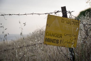 Tehlike mayınları - İsrail 'in Golan Tepeleri' nde, Suriye sınırına yakın bir mayın tarlasının yanında sarı uyarı işareti.