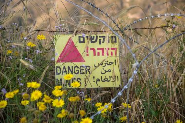 Tehlike mayınları - İsrail 'in Golan Tepeleri' nde, Suriye sınırına yakın bir mayın tarlasının yanında sarı uyarı işareti.