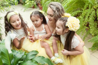 Mutlu kız kardeşleri ve annesi botanik bahçesinde yürüyüş. Sarı etek, büyük bir aile portresi kızlarda