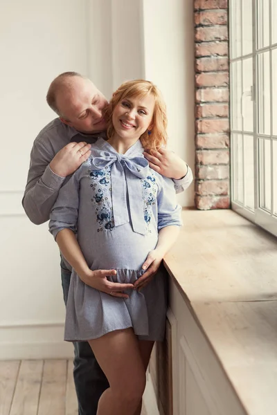 Portret Małżonków Kobieta Ciąży Szczęśliwy Człowiek Stanąć Pobliżu Okna Uścisk — Zdjęcie stockowe