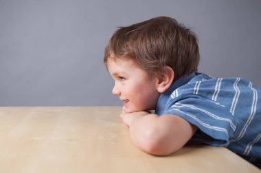 Küçük çocuk portresi. Çocuk tablo, gri arka plan oturuyor