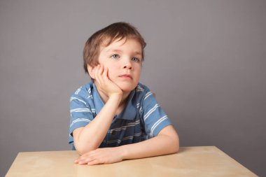 Küçük çocuk portresi. Çocuk tablo, gri arka plan oturuyor