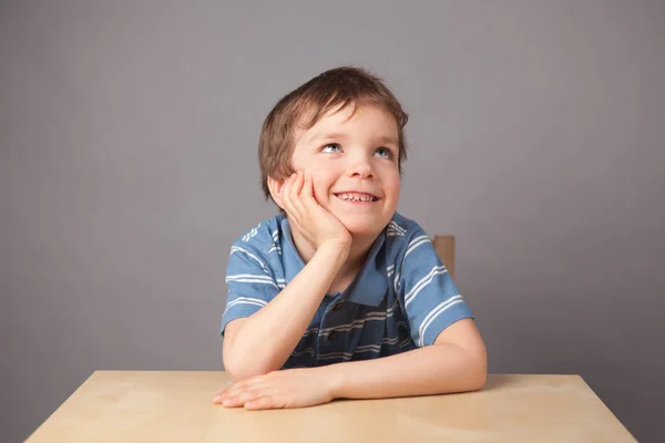 Portret Małego Chłopca Dziecko Siedzi Przy Stole Szary Tło — Zdjęcie stockowe