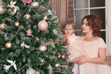 Noel ağacının yanında oturan anne ve mutlu güzel güzel kız portresi