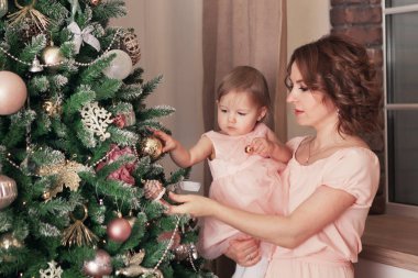 Noel ağacının yanında oturan anne ve mutlu güzel güzel kız portresi