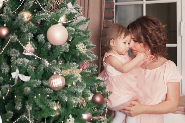 Noel ağacının yanında oturan anne ve mutlu güzel güzel kız portresi