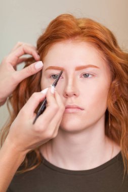 Güzel genç kız bir güzellik salonu düzeltilmesi kaşları var. Kadın düzeltme kaşları formu. Güzel bir kızıl saçlı kız portresi