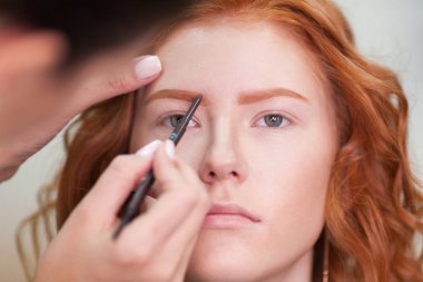 Güzel genç kız bir güzellik salonu düzeltilmesi kaşları var. Kadın düzeltme kaşları formu. Güzel bir kızıl saçlı kız portresi