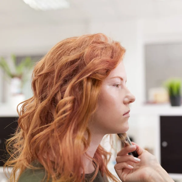 beauty salon, red-haired girl doing make-up and styling in the salon, hairdressers and make-up artist, concept for personal hygiene and beauty