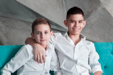 İki kardeş portresi. Çocuklar kanepede kapalı oturuyorsun