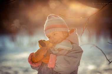 Küçük güzel kırmızı kız kış yürüyüş, çocuk ile yumuşak oyuncak çalış.
