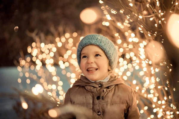 Portret van gelukkig meisje in winteravonden op achtergrond van kerstverlichting — Stockfoto