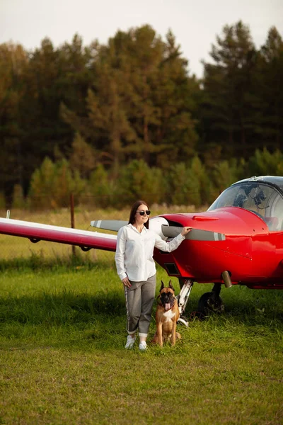 Beautiful girl and dog near airplane. Walk at airport, autumn, outdoor