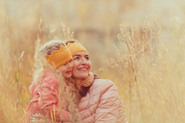 美丽的女孩和母亲在针织皇冠走在秋天的公园 — 图库照片