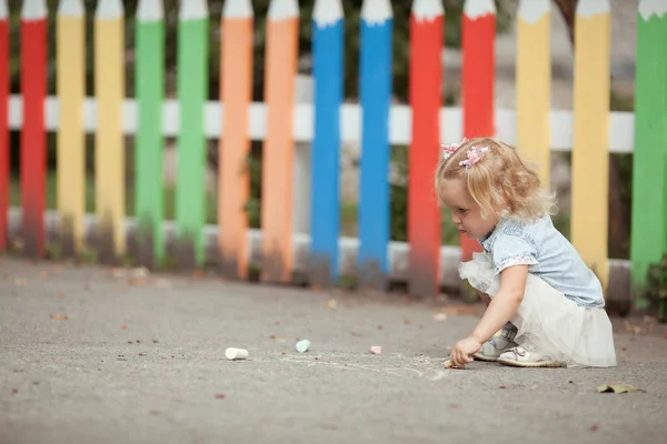 Маленькая Красивая Девочка Рисует Мелом Возле Карандашного Забора Открытом Воздухе — стоковое фото