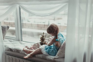 Pencere oturan ve intdoor yumuşak oyuncakla oynamak güzel kız