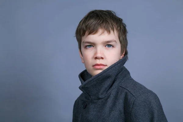 Egy Jóképű Fiú Egy Fekete Kabát Szürke Háttér Beltéri Portré — Stock Fotó