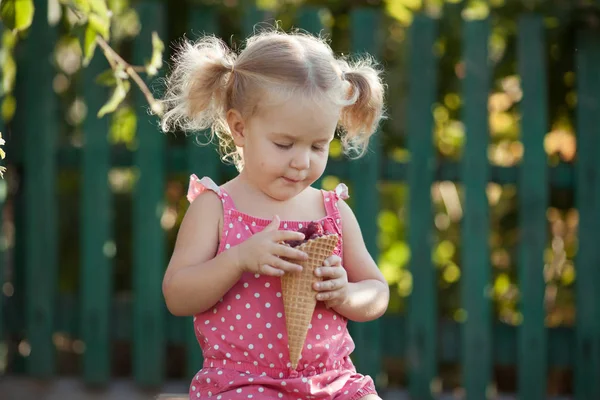 Mutlu küçük kız yaz bahçesinde, açık meyveleri yiyor. — Stok fotoğraf