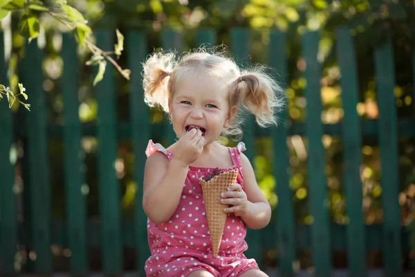 Mutlu küçük kız yaz bahçesinde, açık meyveleri yiyor. — Stok fotoğraf
