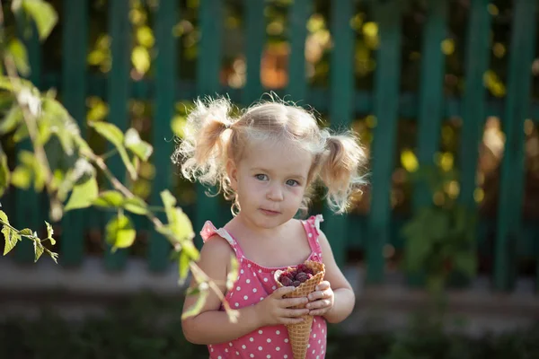 Happy Little Girl jedzą jagody w ogrodzie letnim, na zewnątrz. — Zdjęcie stockowe